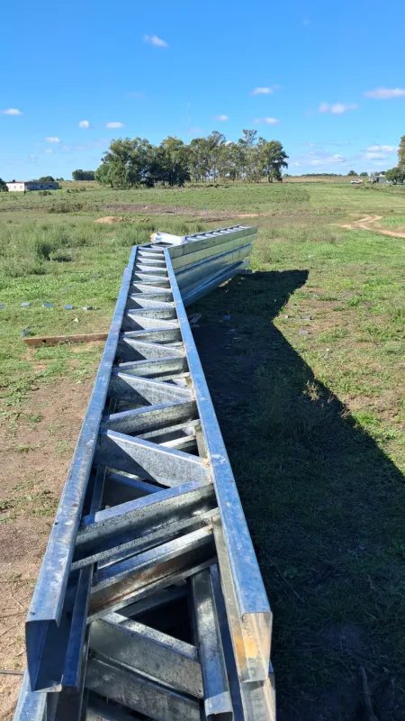 Cerchas reticuladas galvanizadas apiladas sobre el pasto antes del montaje