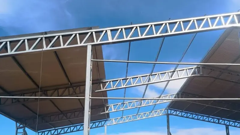 Vista parcial: colocación de chapa de cubierta sobre cerchas de un galpón a dos aguas