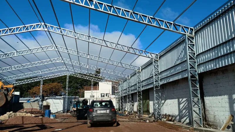 Estructura galvanizada de galpón montada entre dos muros de bloques