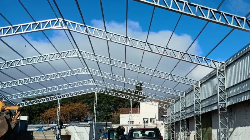 Vista parcial: estructura galvanizada de galpón montada entre dos muros de bloques