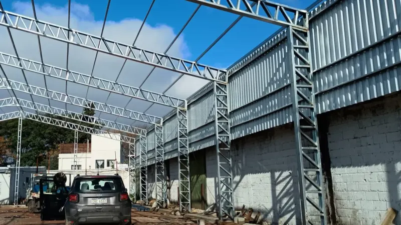 Otro ángulo: estructura galvanizada de galpón montada entre dos muros de bloques