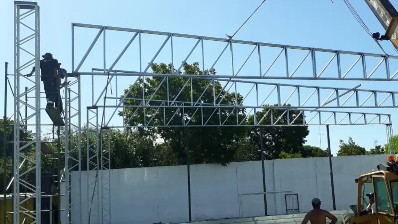 Vista parcial: montaje de cerchas con manipulador telescópico y operarios en altura